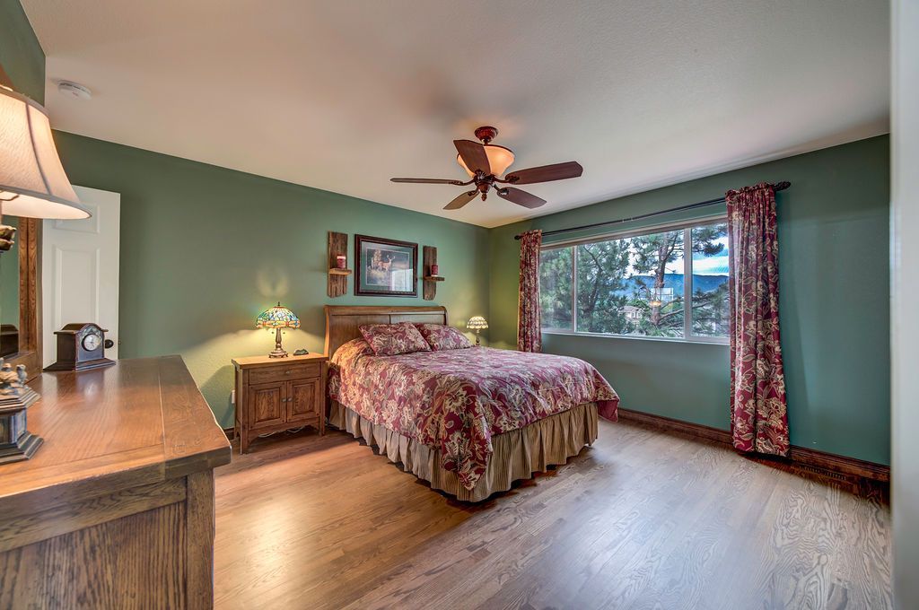 A bedroom with a bed , dresser , lamp and ceiling fan.