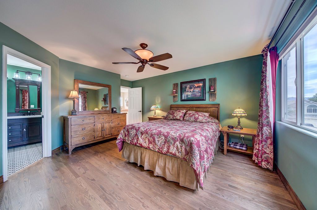 A bedroom with a bed , dresser , mirror and ceiling fan.