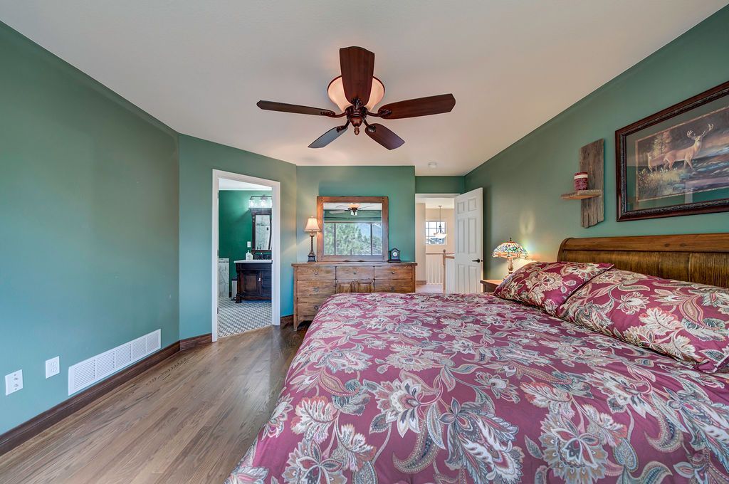 A bedroom with a bed , dresser , mirror and ceiling fan.