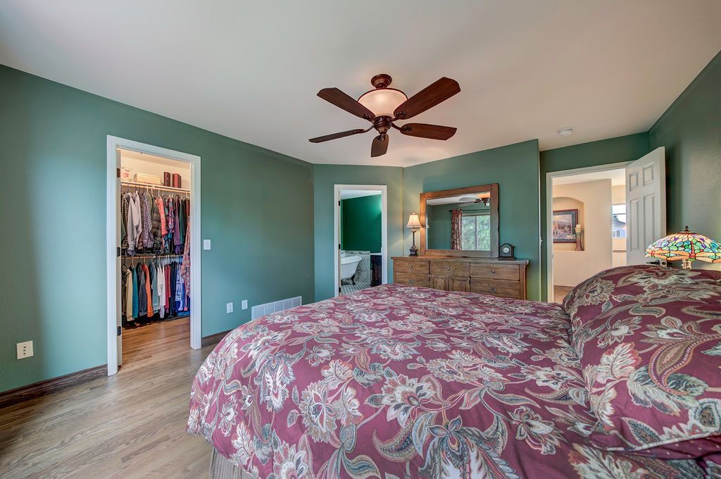 A bedroom with a bed , dresser , mirror and ceiling fan.