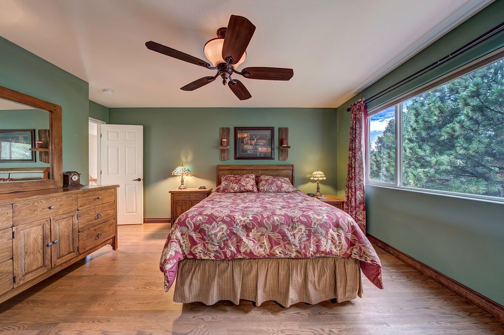 A bedroom with a bed , dresser , mirror and ceiling fan.