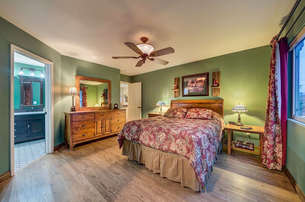 A bedroom with a bed , dresser , mirror and ceiling fan.