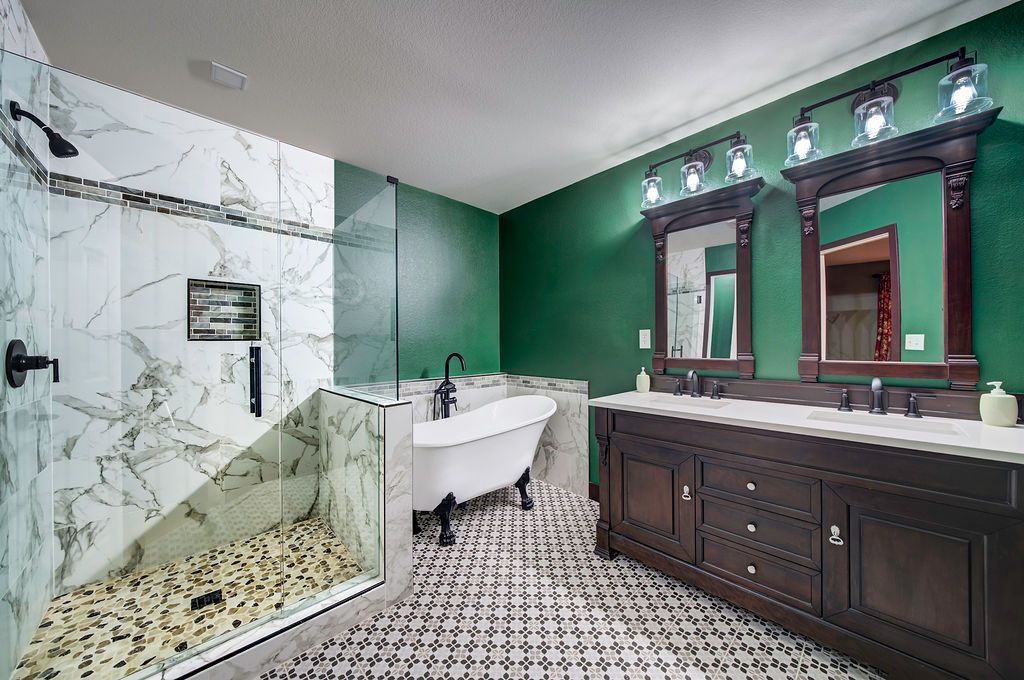 A bathroom with green walls , two sinks , a tub , and a walk in shower.