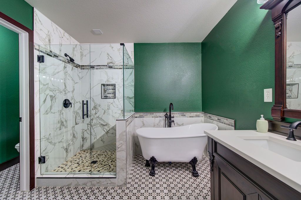 A bathroom with green walls , a bathtub , a sink , and a walk in shower.
