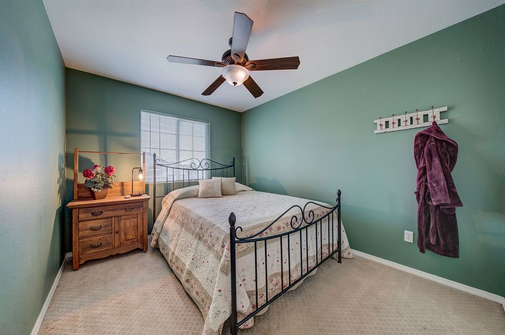 A bedroom with a bed , dresser , nightstand and ceiling fan.