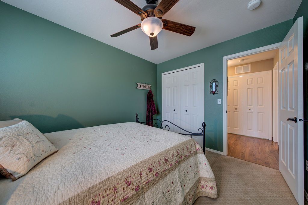 A bedroom with a bed and a ceiling fan.