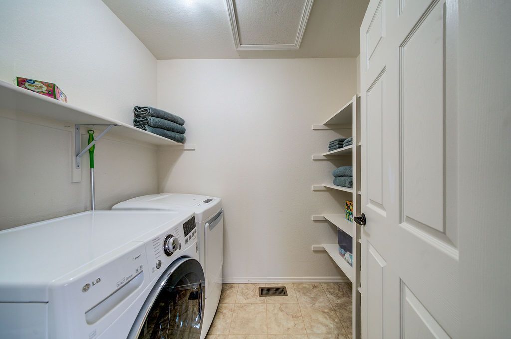 A laundry room with a washer and dryer and shelves.