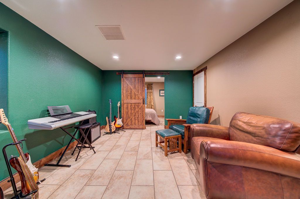 A living room with a keyboard , guitars , chairs and a sliding barn door.