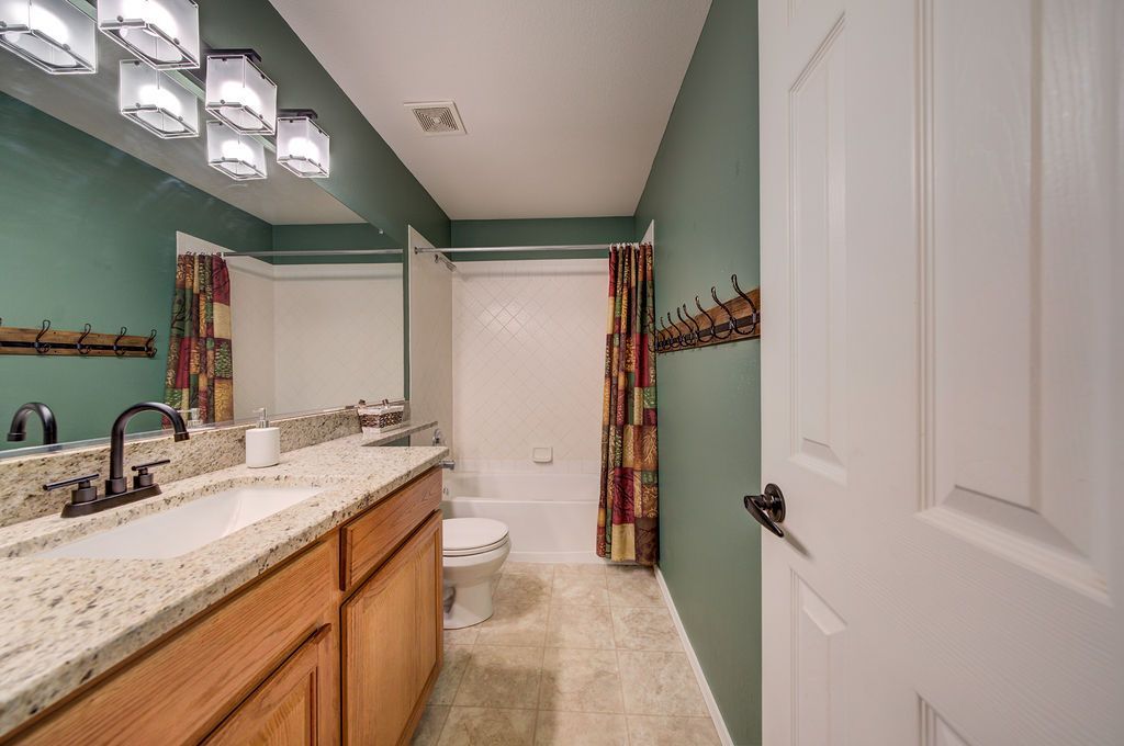 A bathroom with a sink , toilet , shower and mirror.