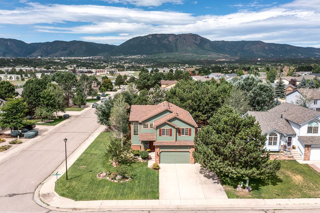 An aerial view of a house in a residential area with mountains in the background.