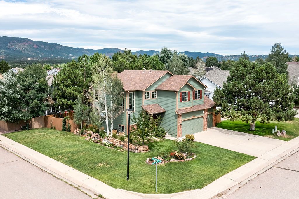 An aerial view of a house in a residential area with mountains in the background.