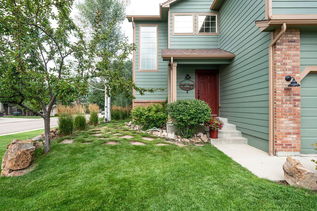 A green house with a red door and a lush green lawn
