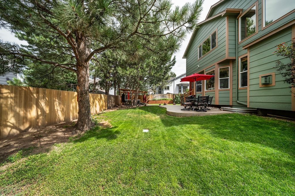 The backyard of a house with a lush green lawn and a wooden fence.
