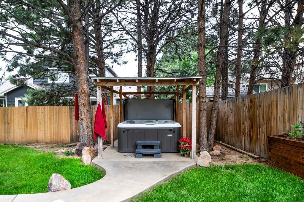 A hot tub is sitting under a pergola in a backyard.