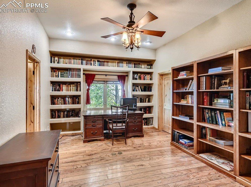 A large room with lots of bookshelves and a ceiling fan.