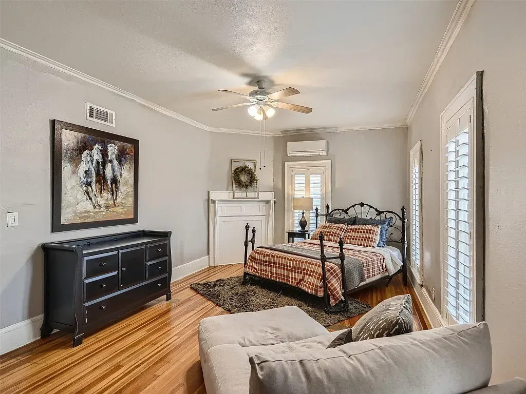 A bedroom with a bed , couch , dresser and fireplace.