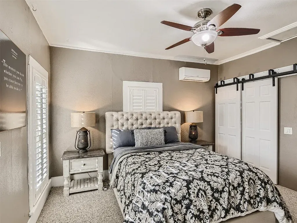 A bedroom with a bed , nightstand , ceiling fan and sliding barn doors.