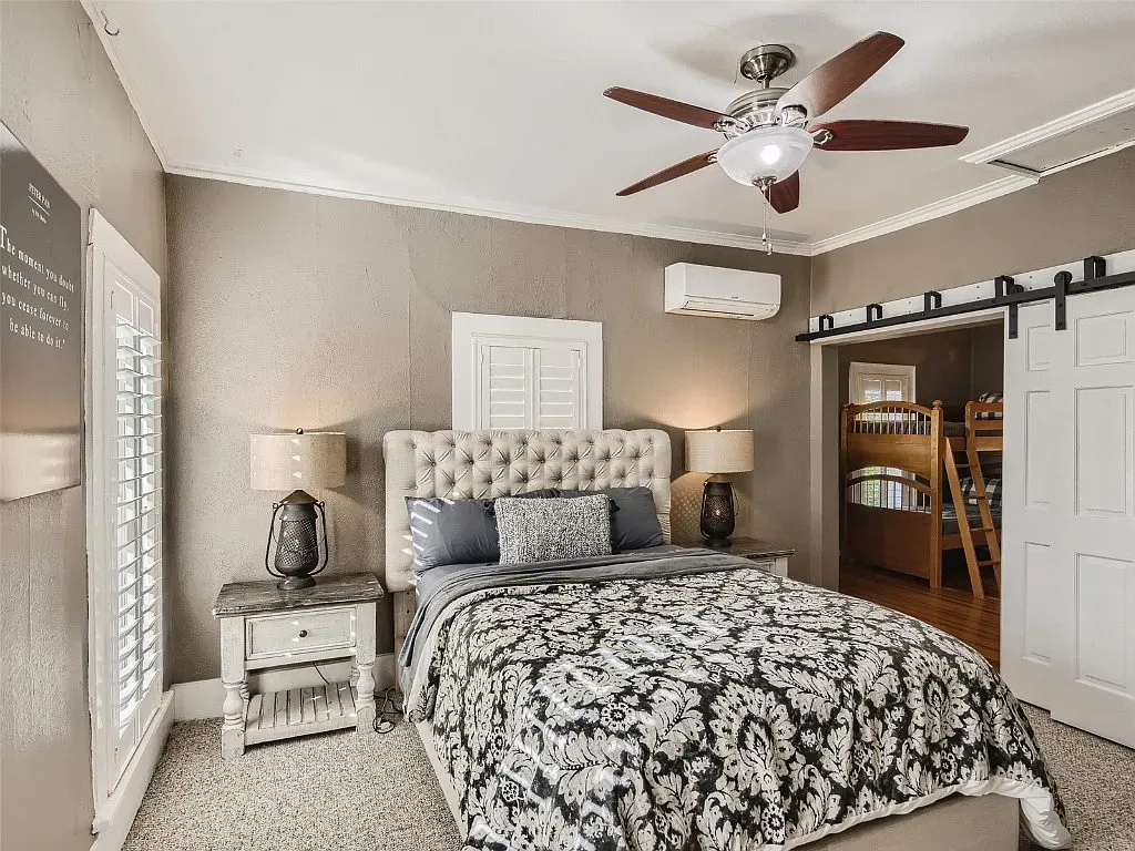 A bedroom with a bed , nightstand , ceiling fan and bunk beds.