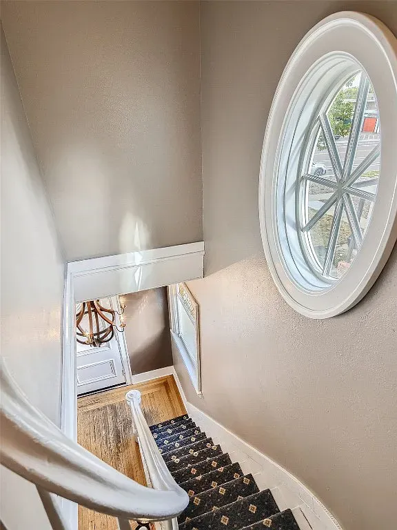 A staircase with a round window on the wall.