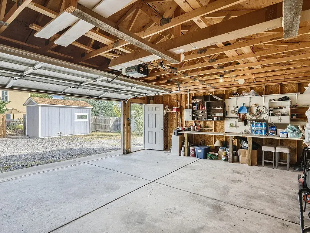 A large empty garage with a shed in the background.
