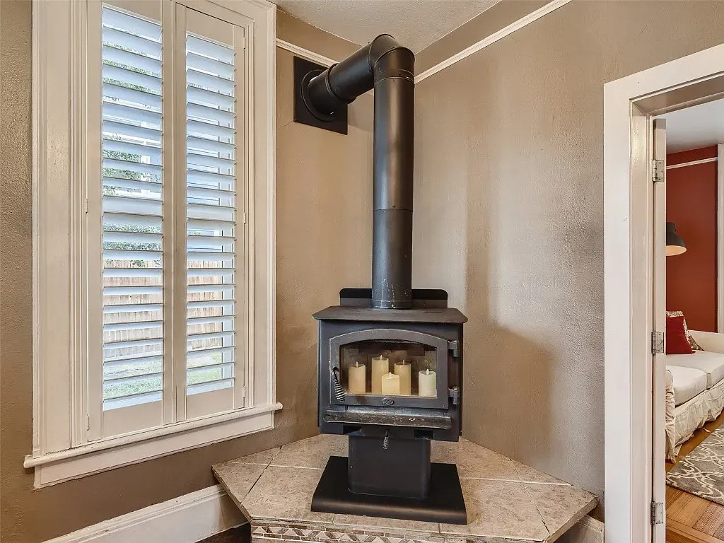 A wood stove is sitting in the corner of a room next to a window.