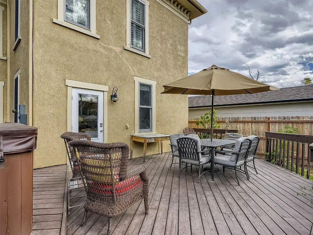 A wooden deck with a table and chairs and an umbrella in front of a house.