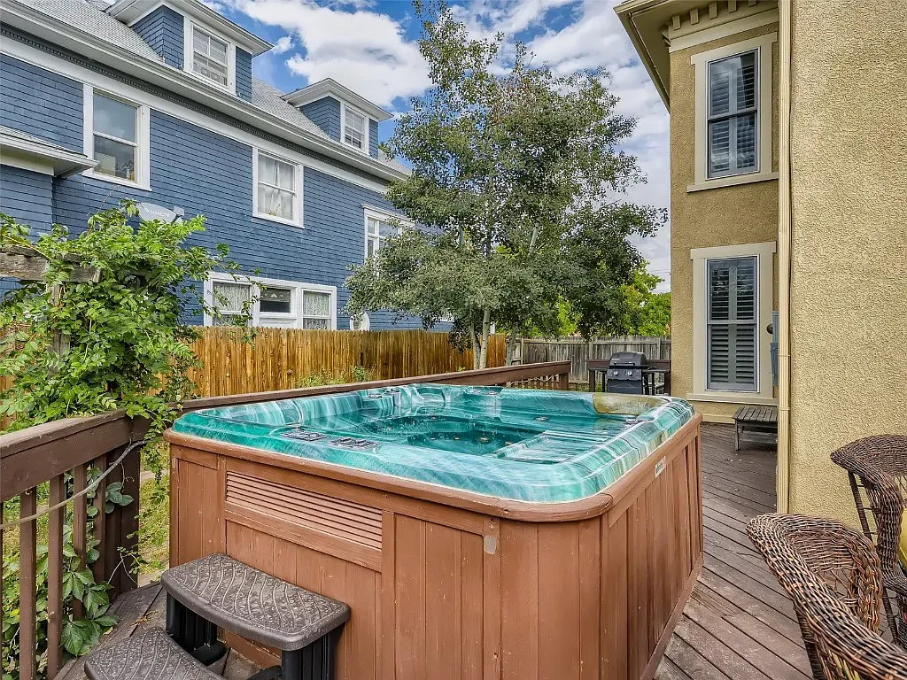 A hot tub is sitting on a deck in front of a house.