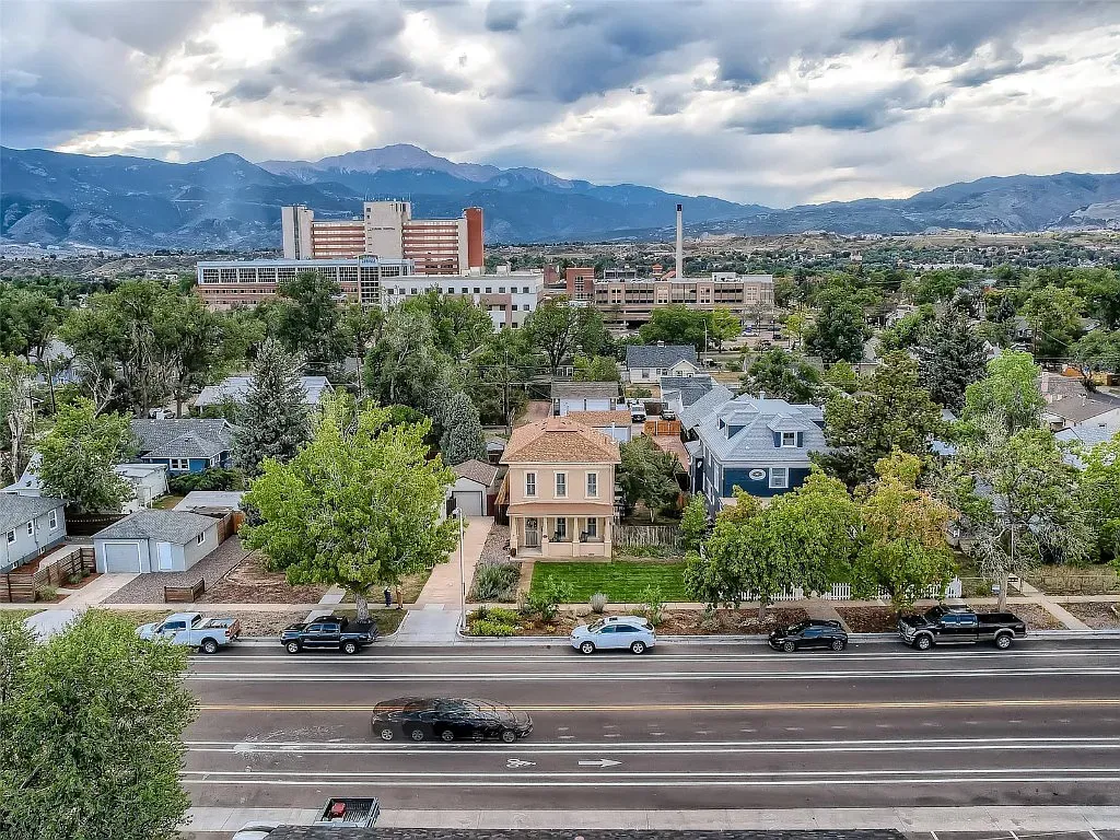 An aerial view of a city with mountains in the background and a house in the foreground.