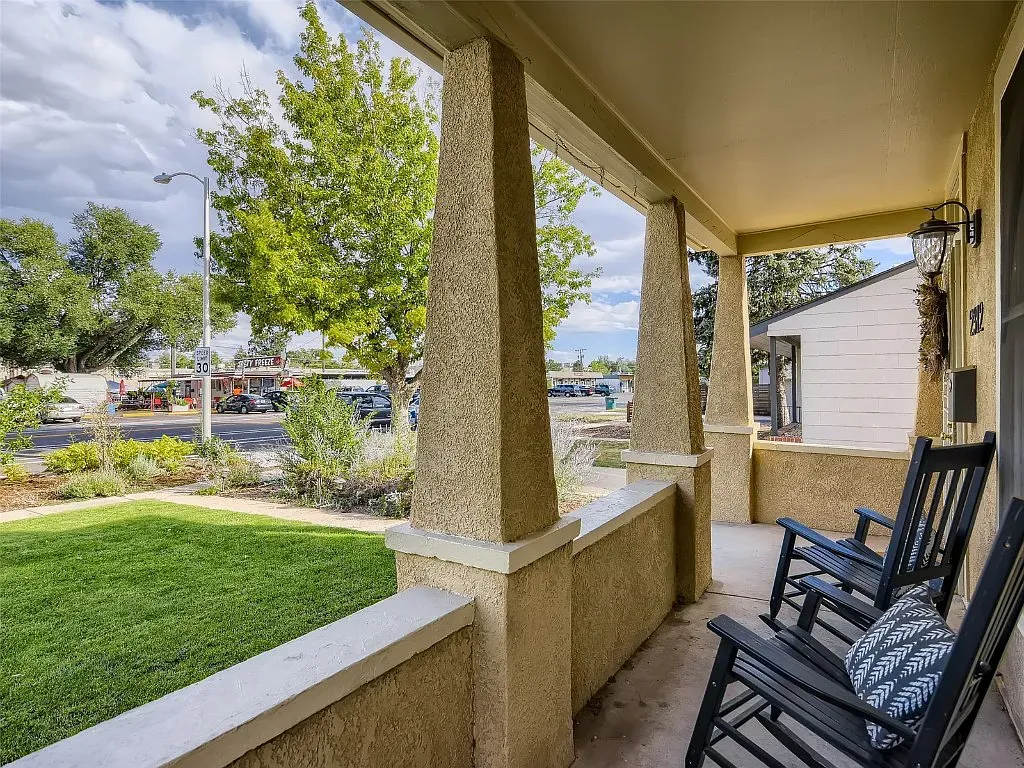 There are two rocking chairs on the porch of a house.