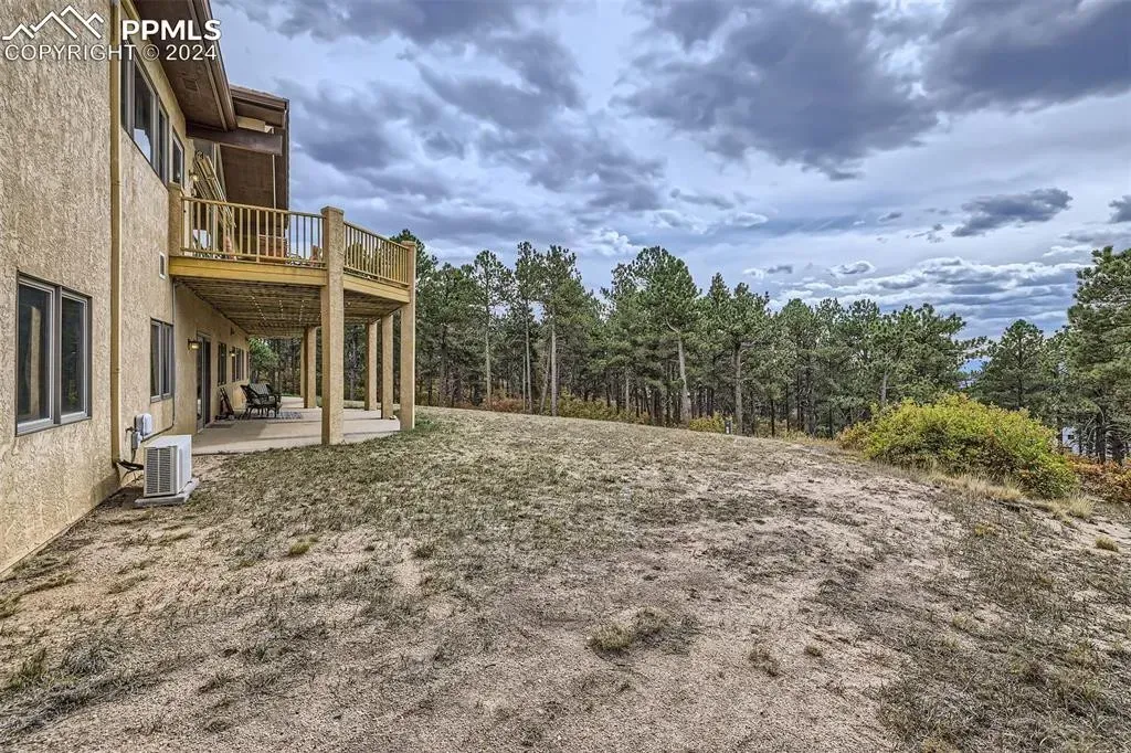The backyard of a house with a large deck and trees in the background.