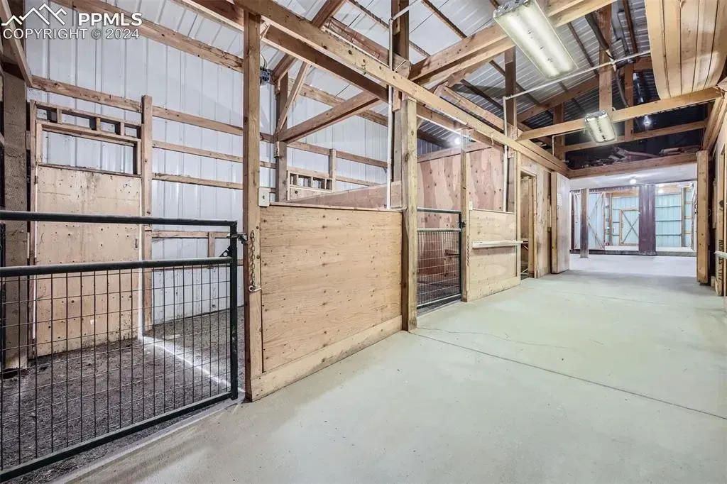 A large empty barn with wooden walls and a metal fence.