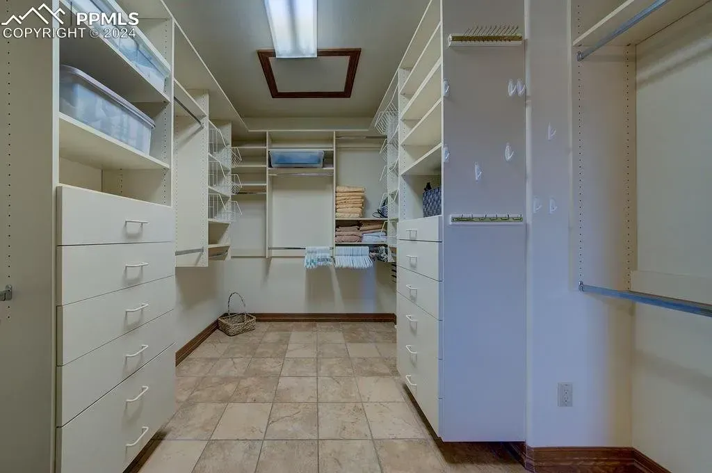 A large walk in closet with lots of shelves and drawers.
