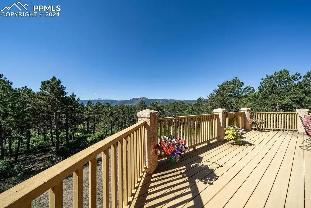 A wooden deck with a railing and flowers on it