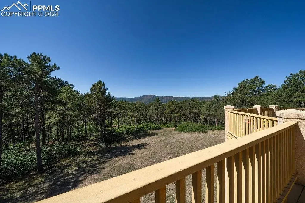 A wooden deck with a view of a forest and mountains.