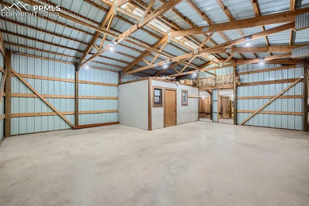 A large empty barn with a metal roof and wooden beams.
