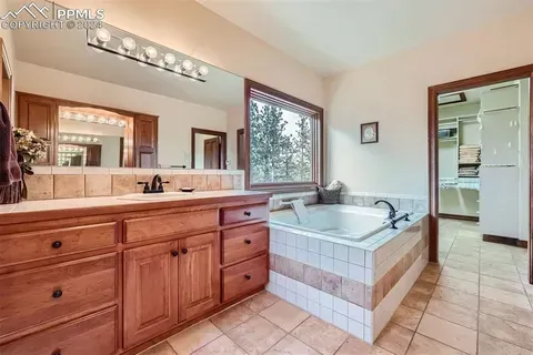 A bathroom with two sinks , a tub and a large mirror.