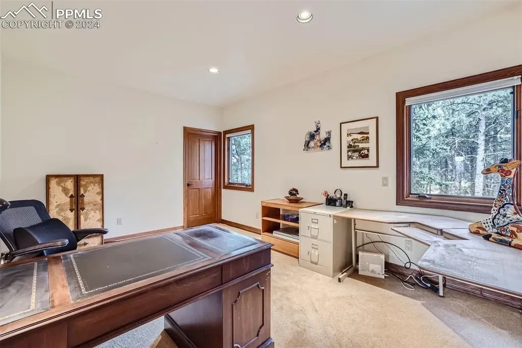 A home office with a large desk and a large window