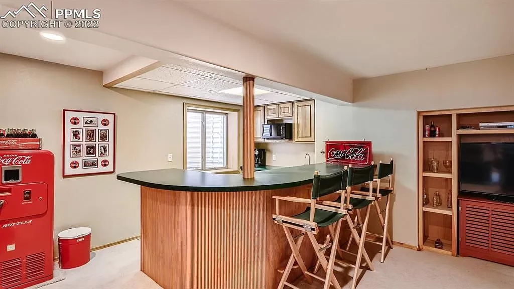A basement with a bar and chairs and a coca cola machine.