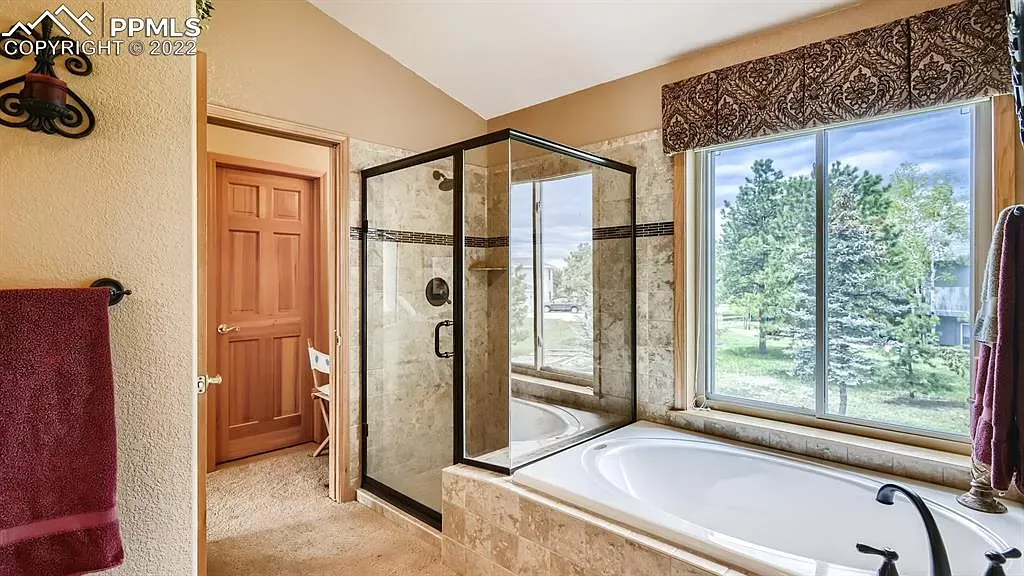 A bathroom with a tub , shower , and window.