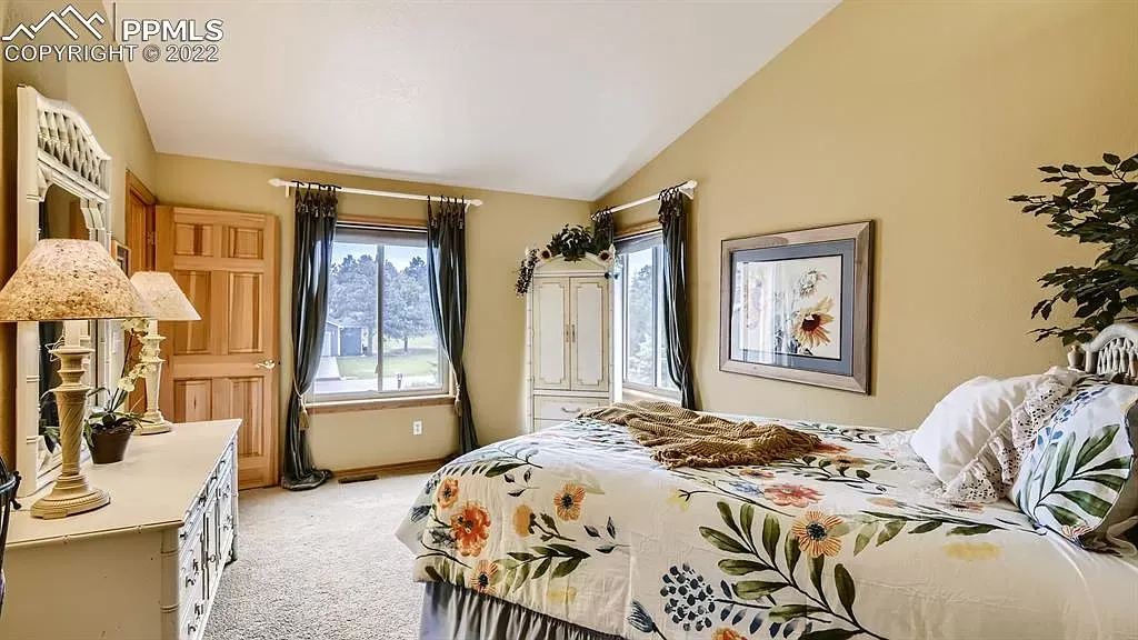 A bedroom with a large bed , dresser , mirror and lamps.