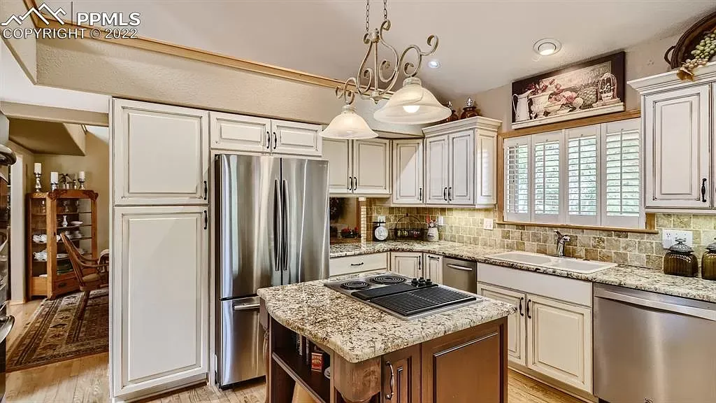 A kitchen with white cabinets , granite counter tops , stainless steel appliances and a large island.