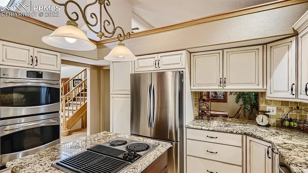 A kitchen with granite counter tops , stainless steel appliances , and white cabinets.