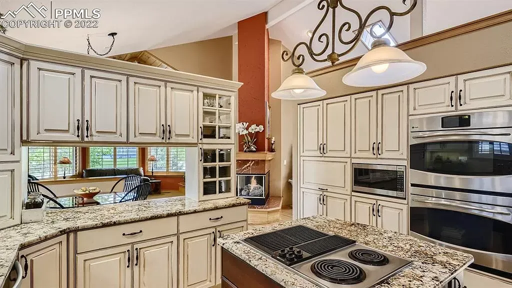 A kitchen with white cabinets , granite counter tops , stainless steel appliances and a large island.