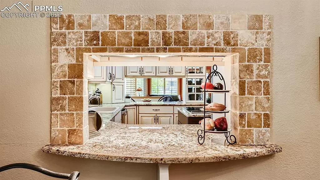 A view of a kitchen through a window with a granite counter top.