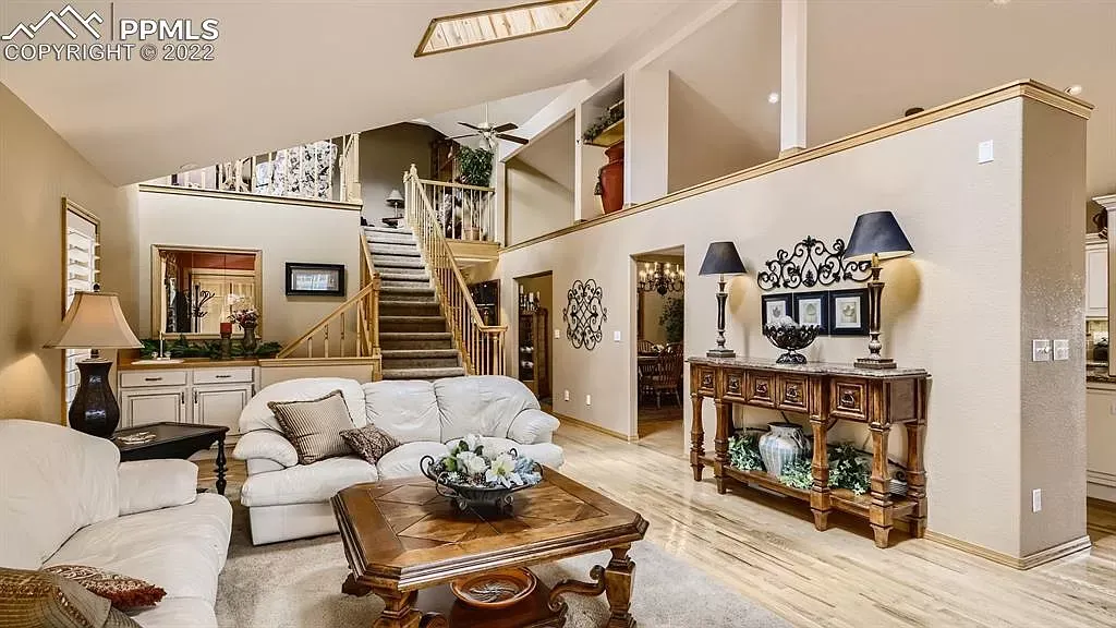 A living room with a couch , coffee table , lamps and stairs.