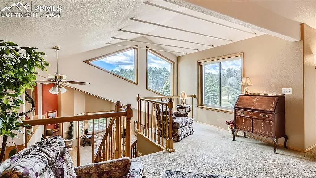 A living room with a couch , chairs , stairs and a piano.