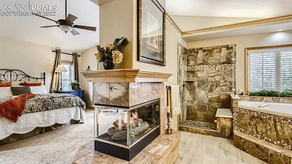A bedroom with a fireplace , bathtub , and ceiling fan.