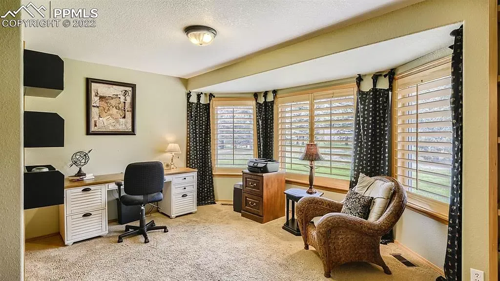 A living room with a wicker chair a desk and a lamp