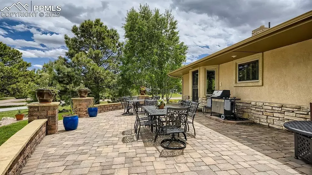 A large patio with tables and chairs in front of a house.