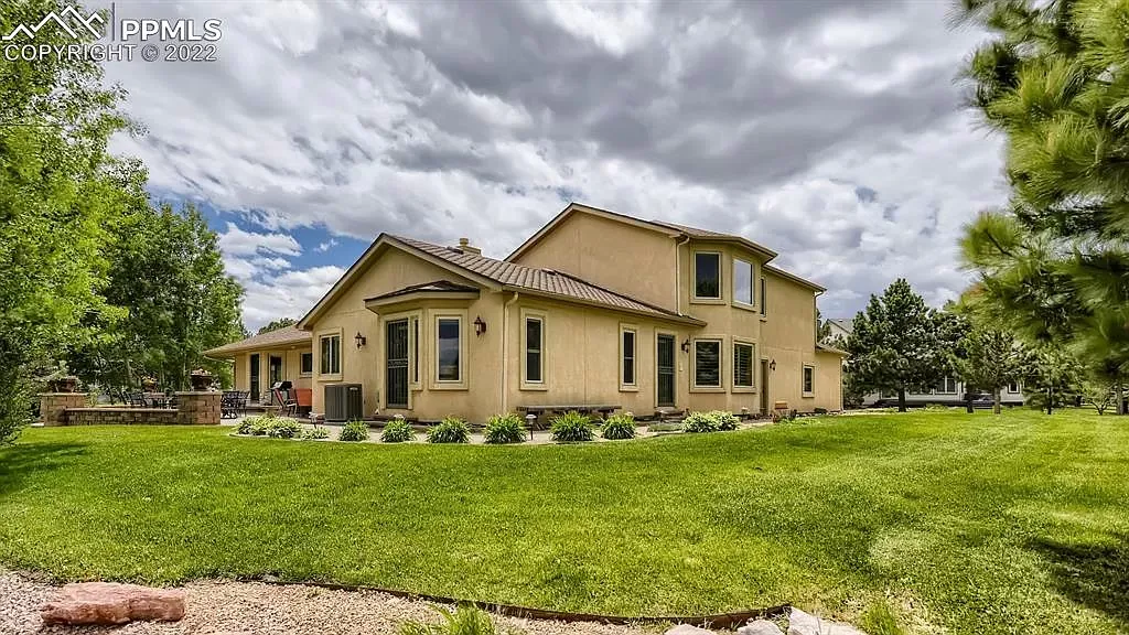 A large house is sitting on top of a lush green field.